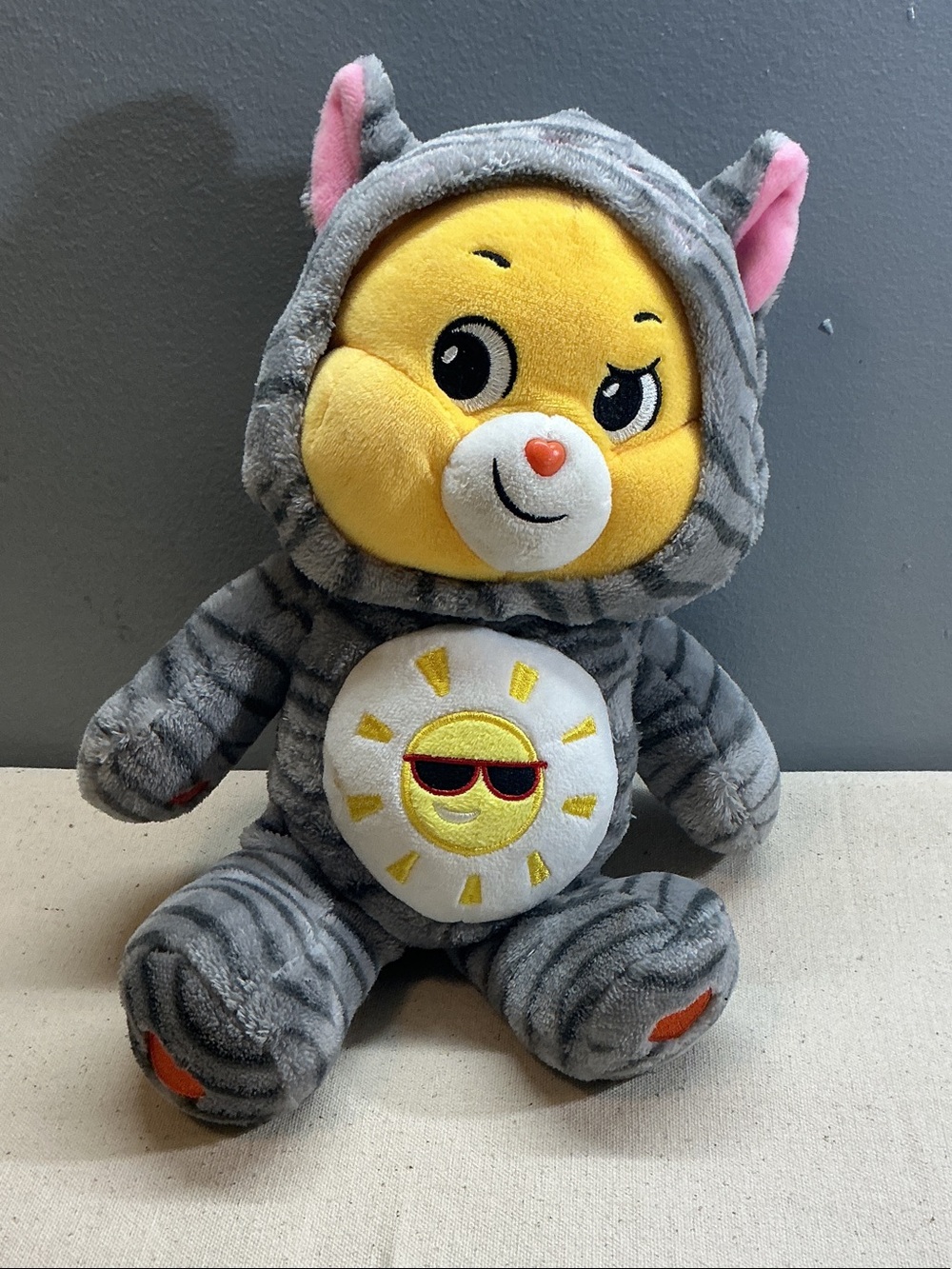Care Bears fun shine bear wearing a gray tiger-stripes kitty